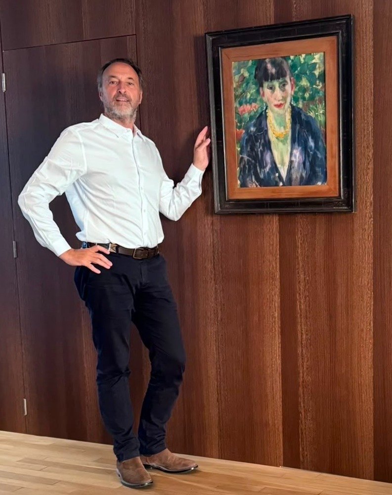 Olivier Bertrand standing beside a painting by Rik Wouters