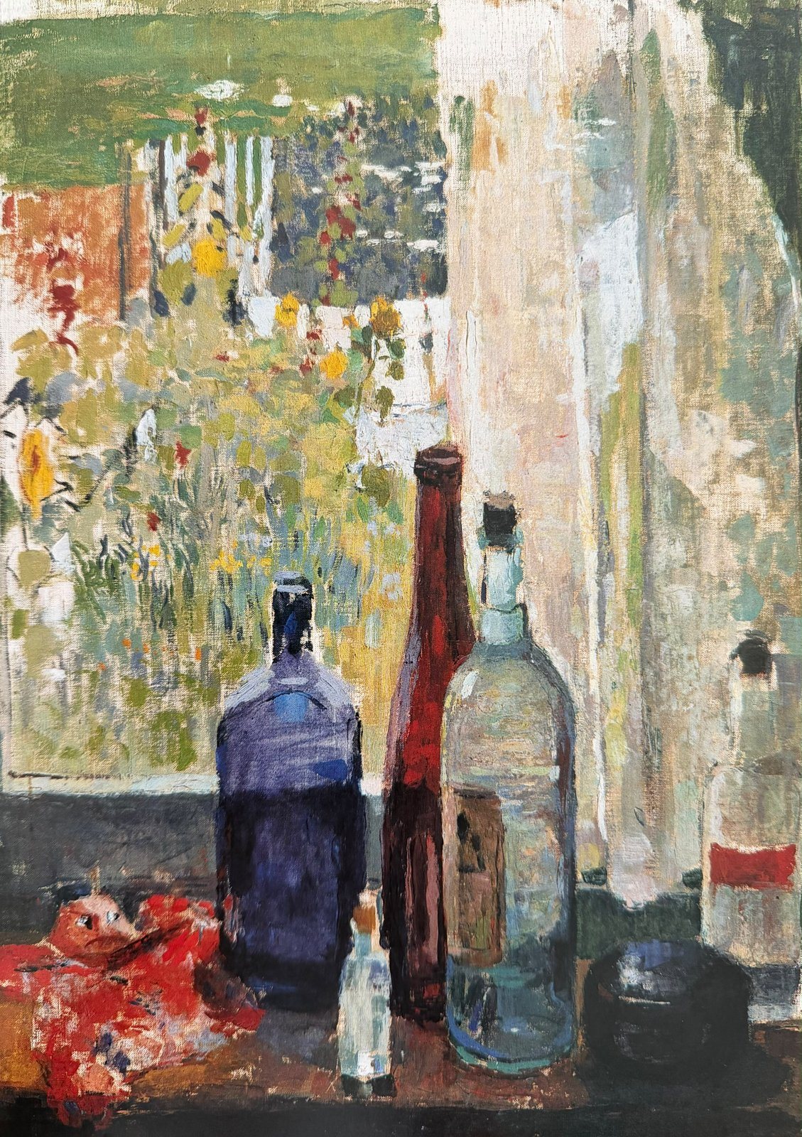 Still life of blue, red and clear bottles on a windowsill before a sunlit garden