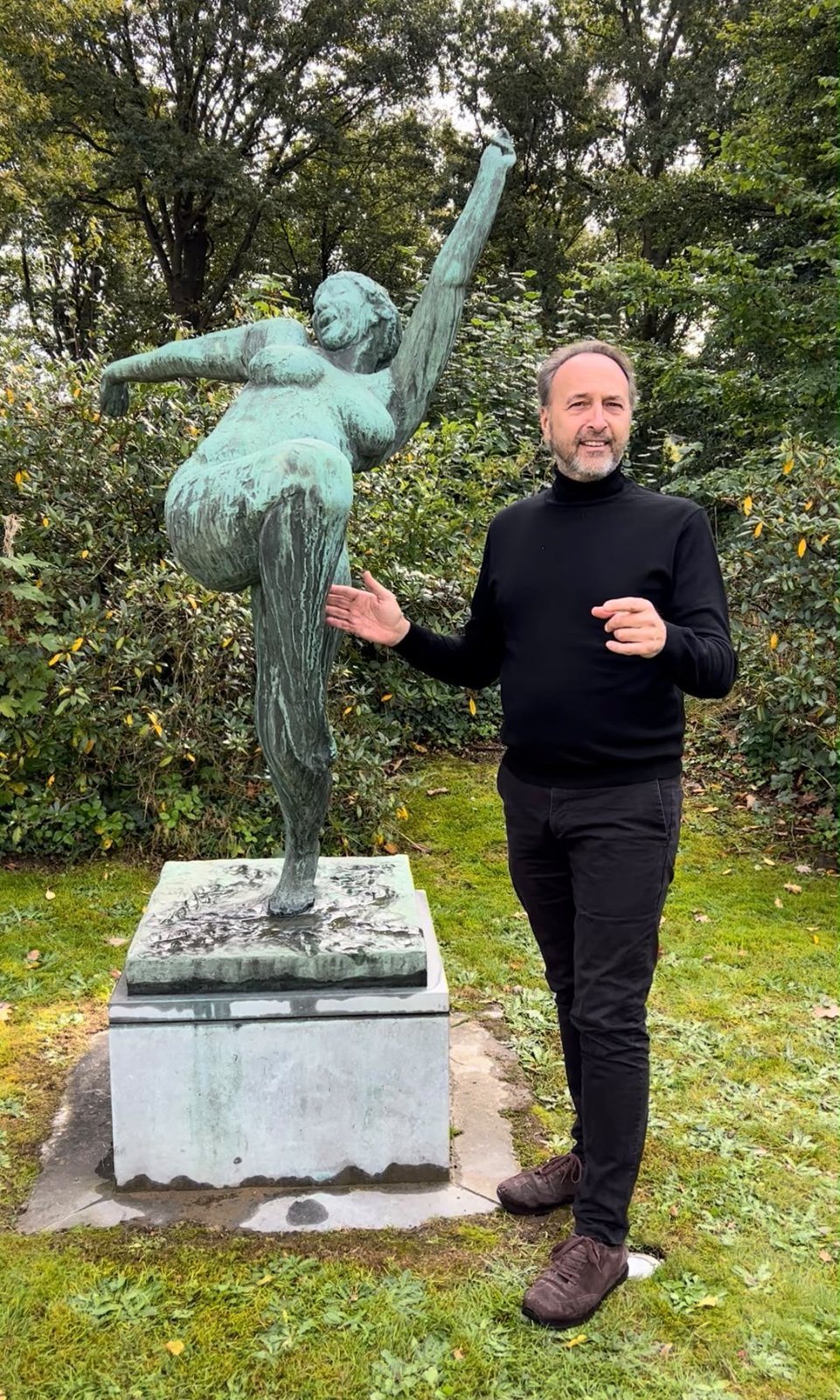 Bronze sculpture of a dancing woman, one leg raised, with Olivier Bertrand standing beside it
