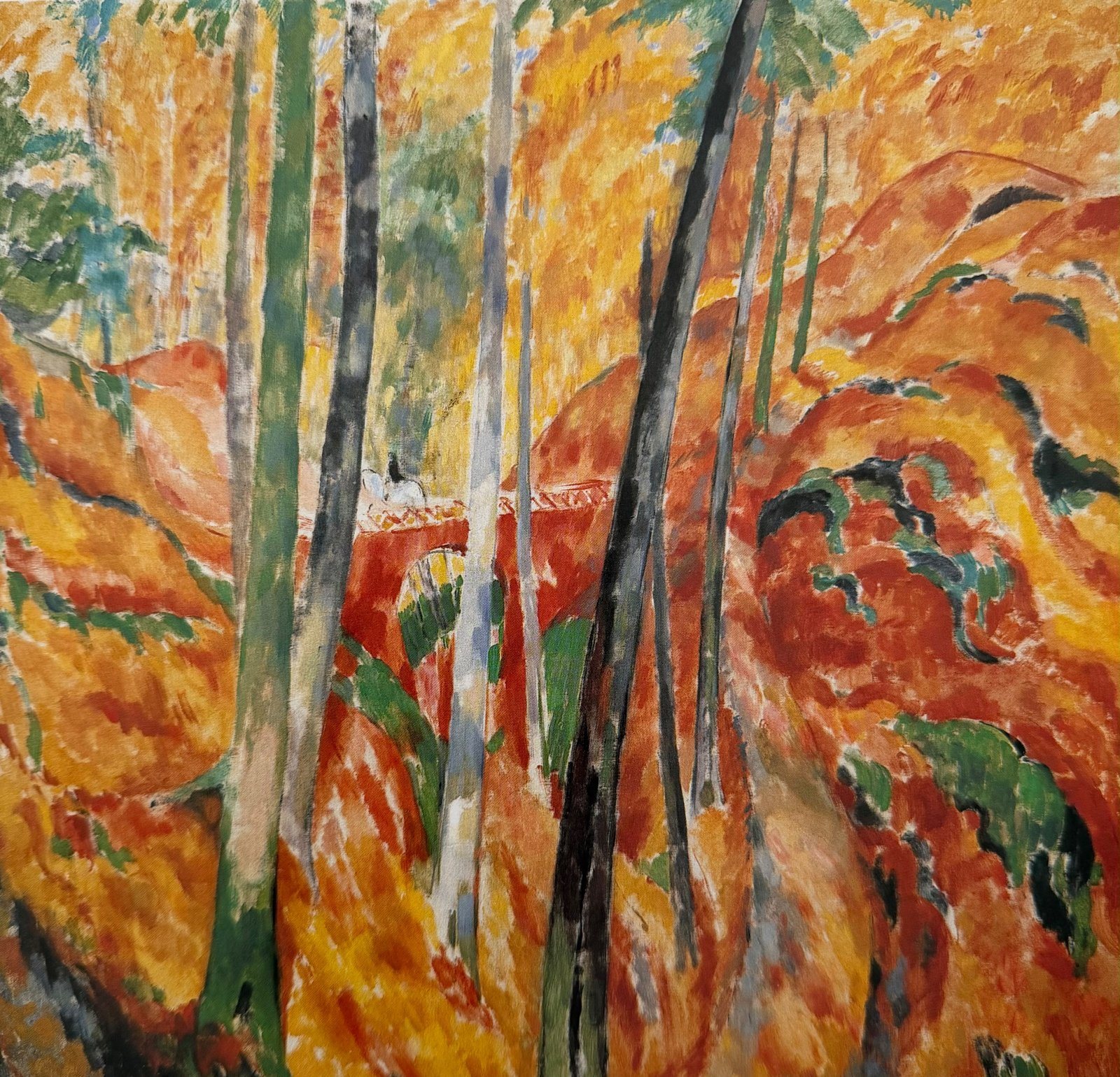 Forest in orange and red autumn colours, with slender trunks and a red viaduct
